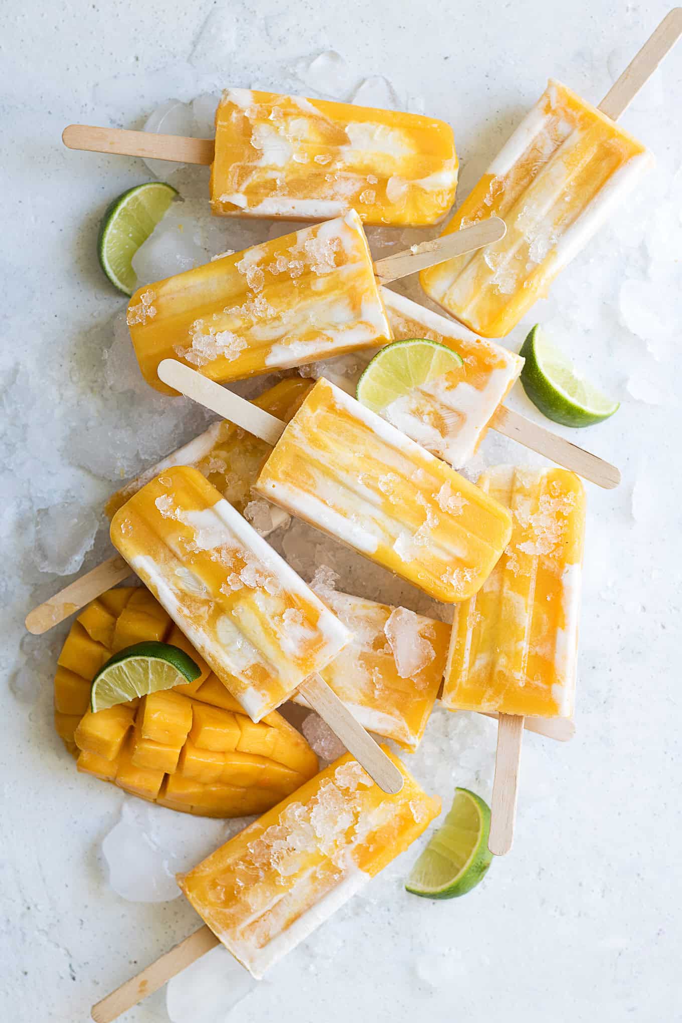 mango popsicles on ice with limes and mango.