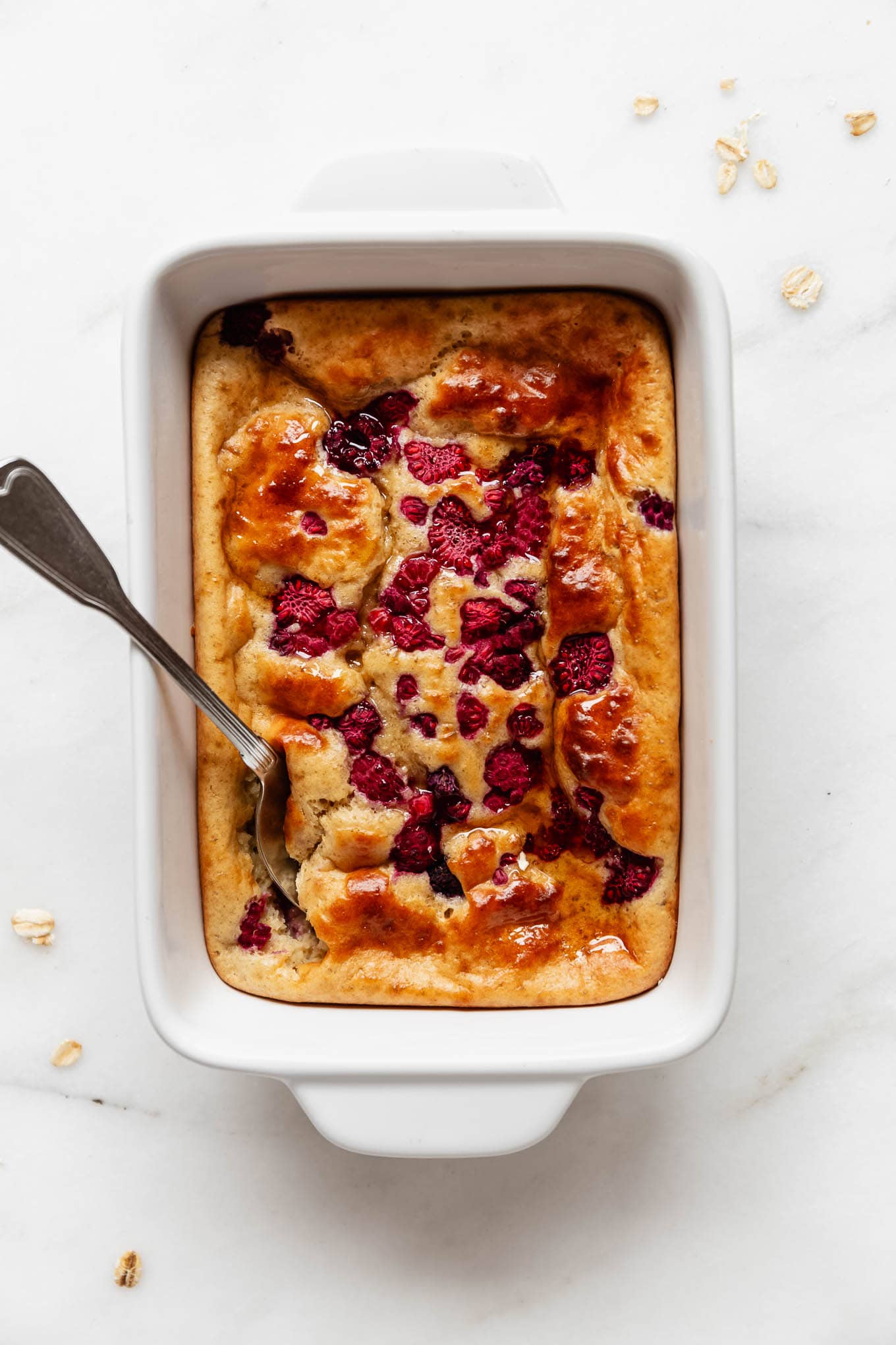 a pancake bowl with raspberries in a white baking dish.