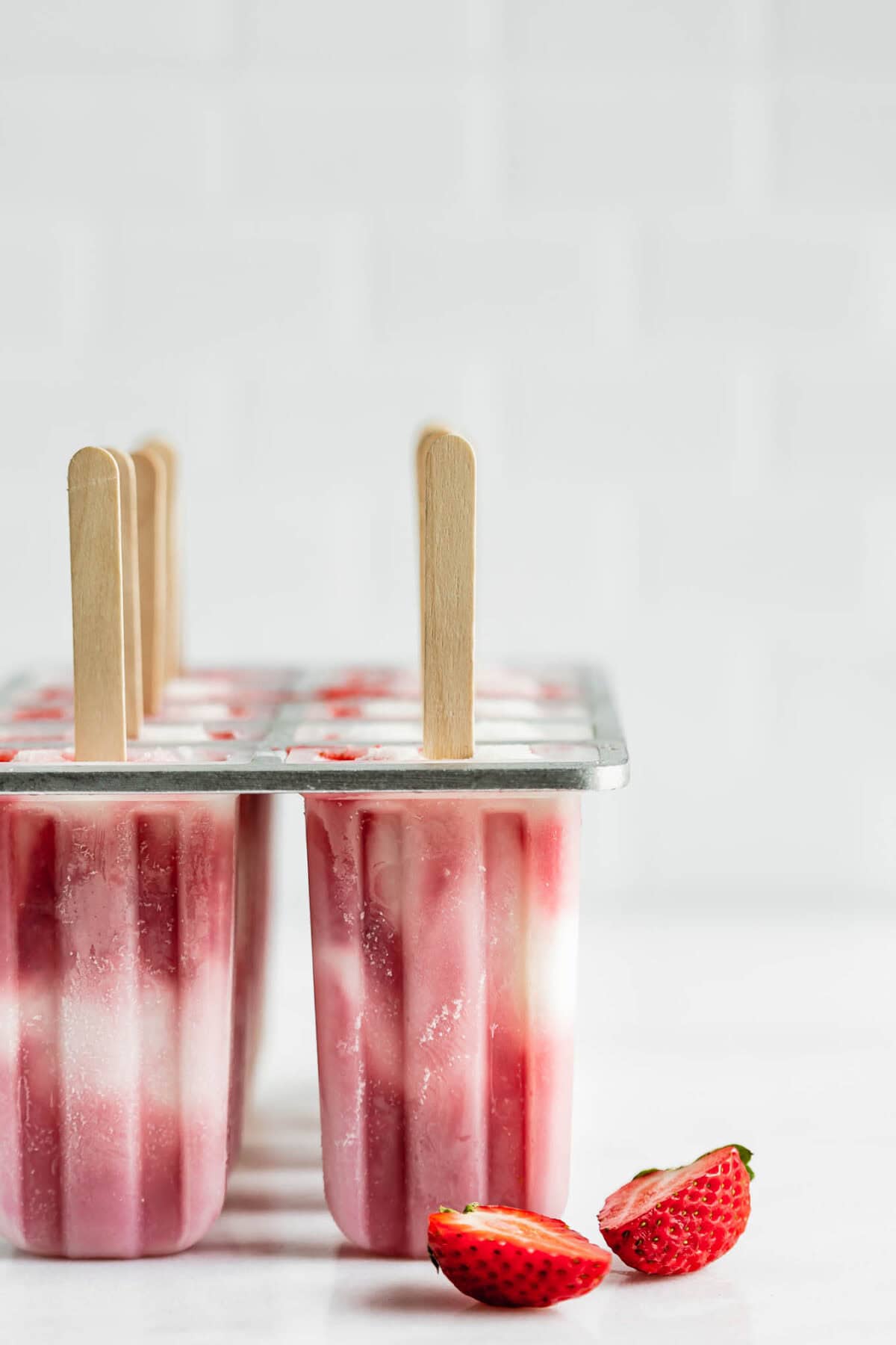 strawberry cheesecake popsicles in a popsicle mold.