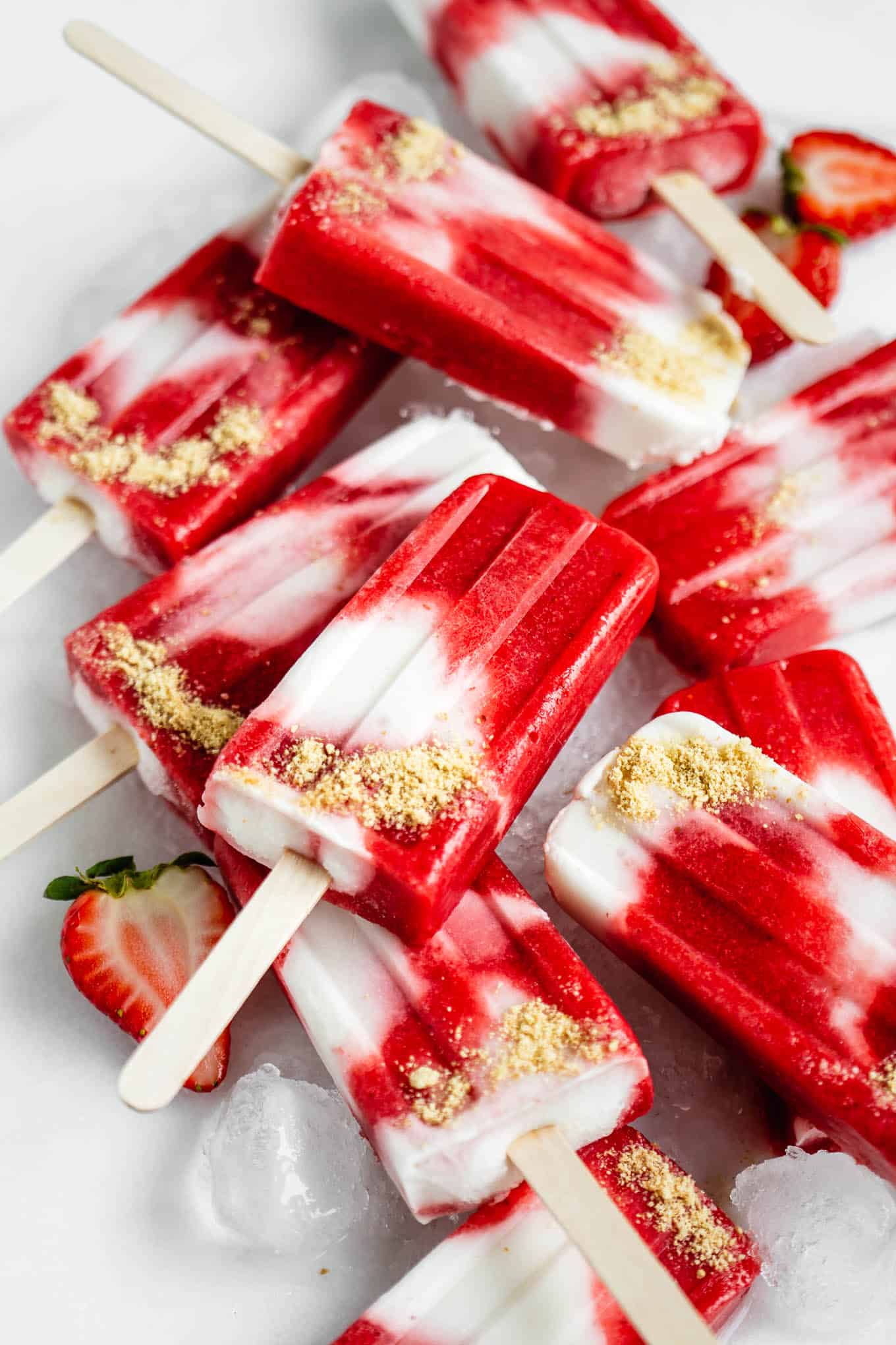 Strawberry cheesecake popsicles topped with graham cracker crumbs.