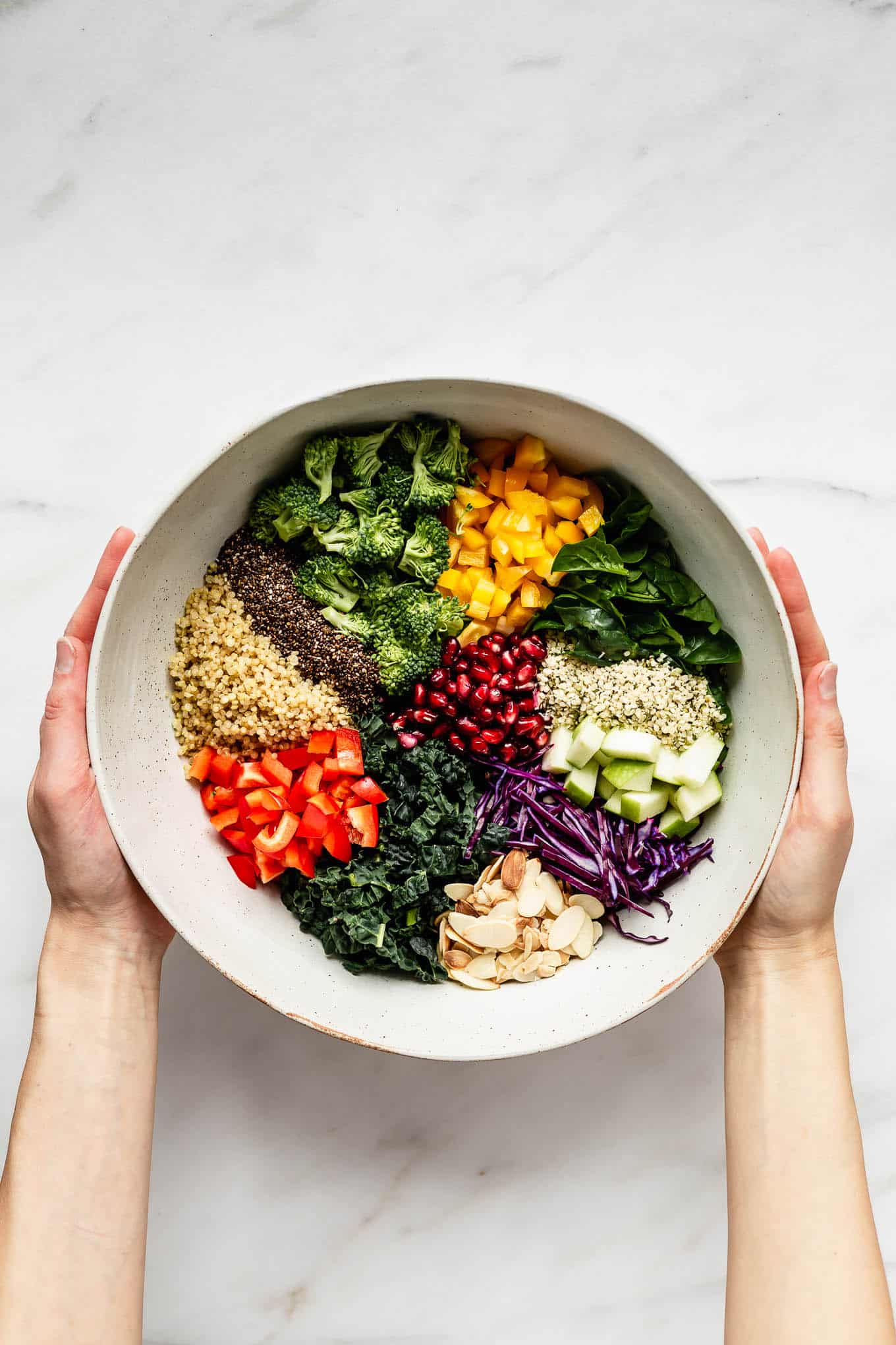 two hands holding a bowl of superfood salad.