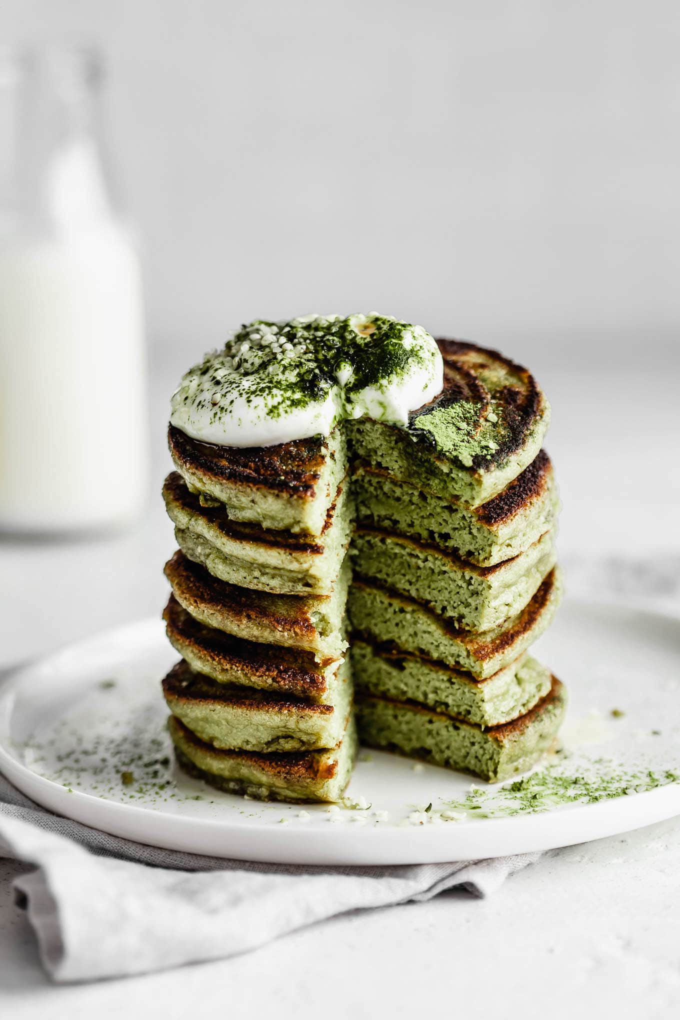 A stack of matcha pancakes topped with yogurt.