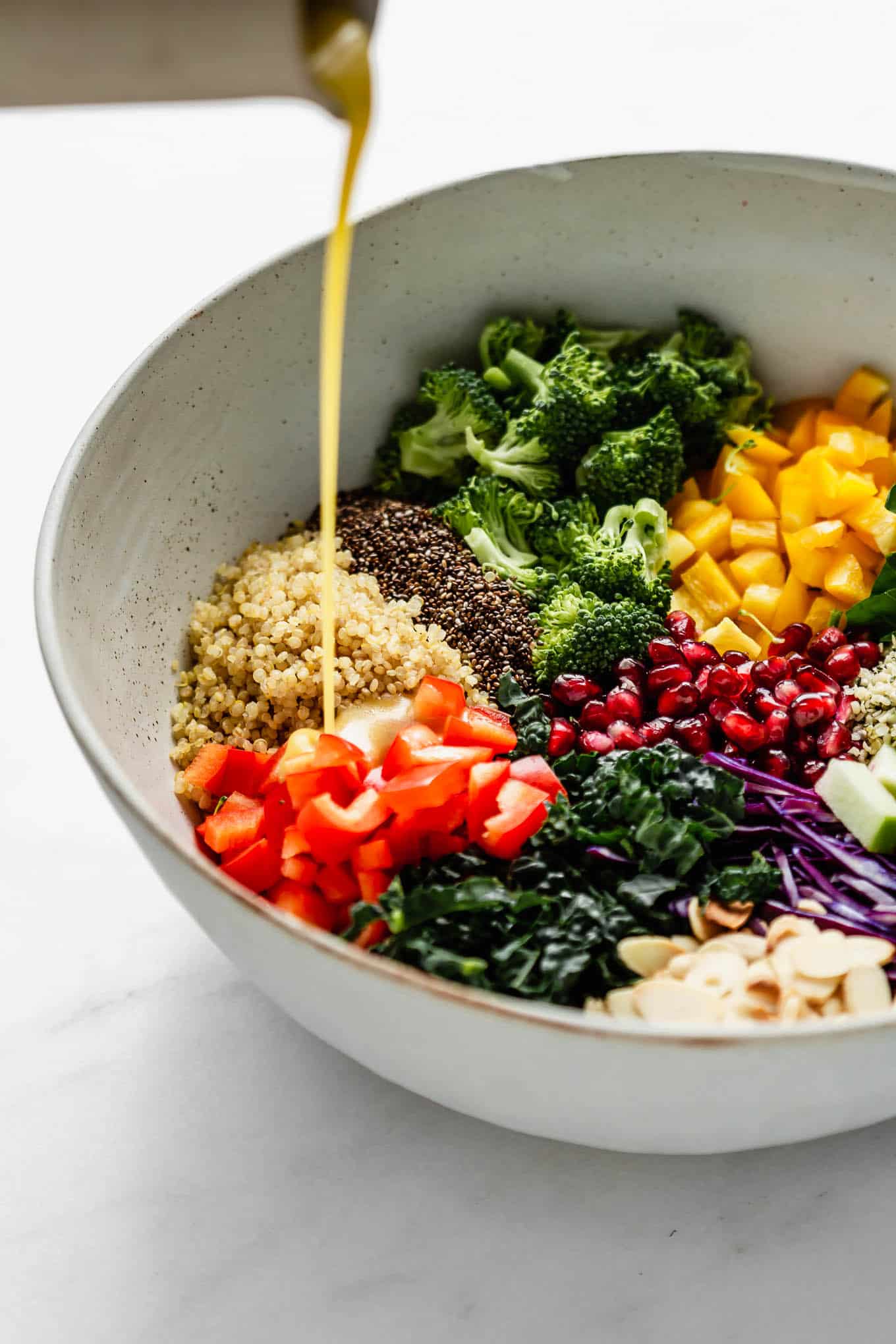 dressing being poured into a bowl of superfood salad.