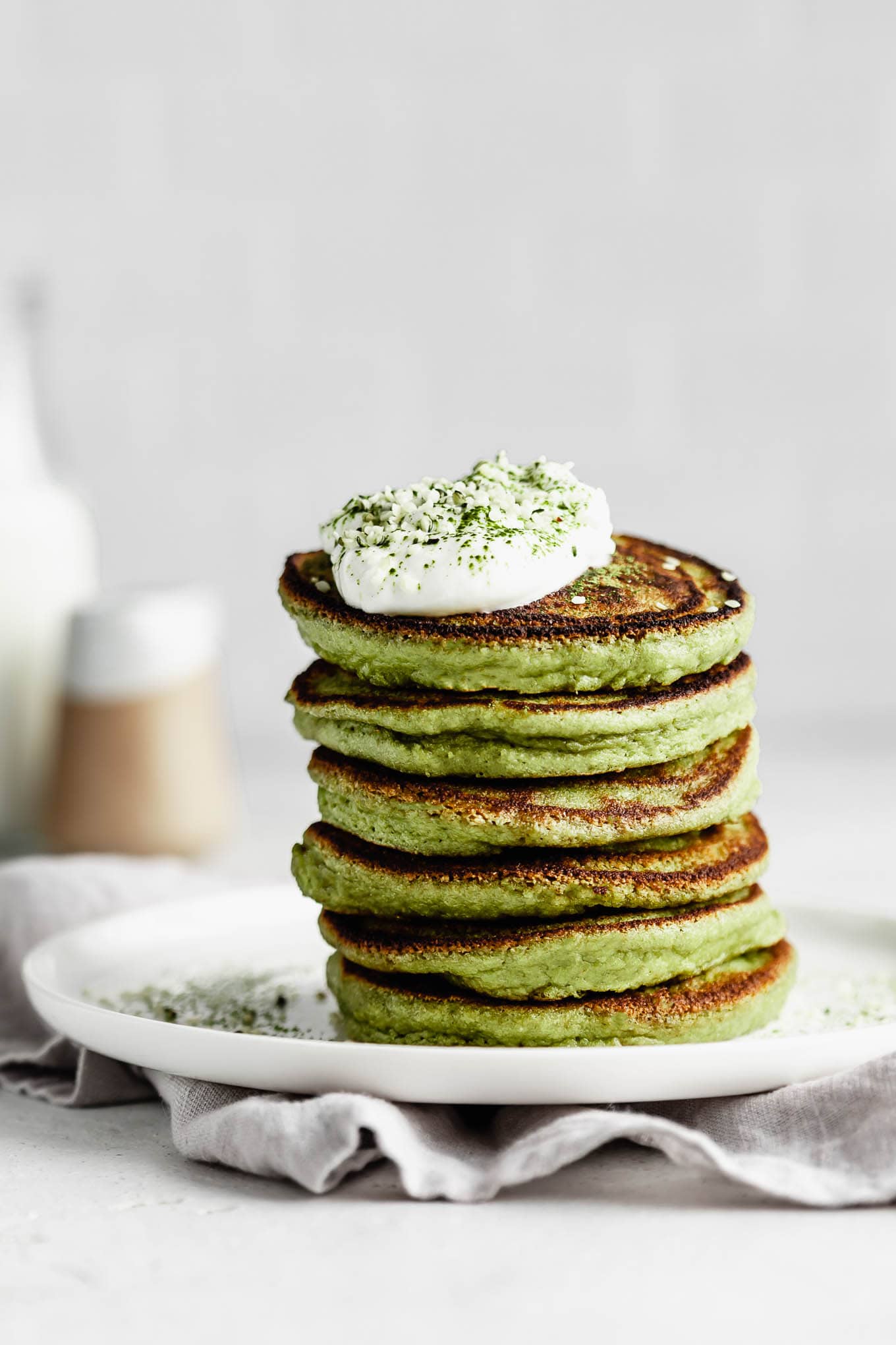 a stack of matcha pancakes on a white plate.