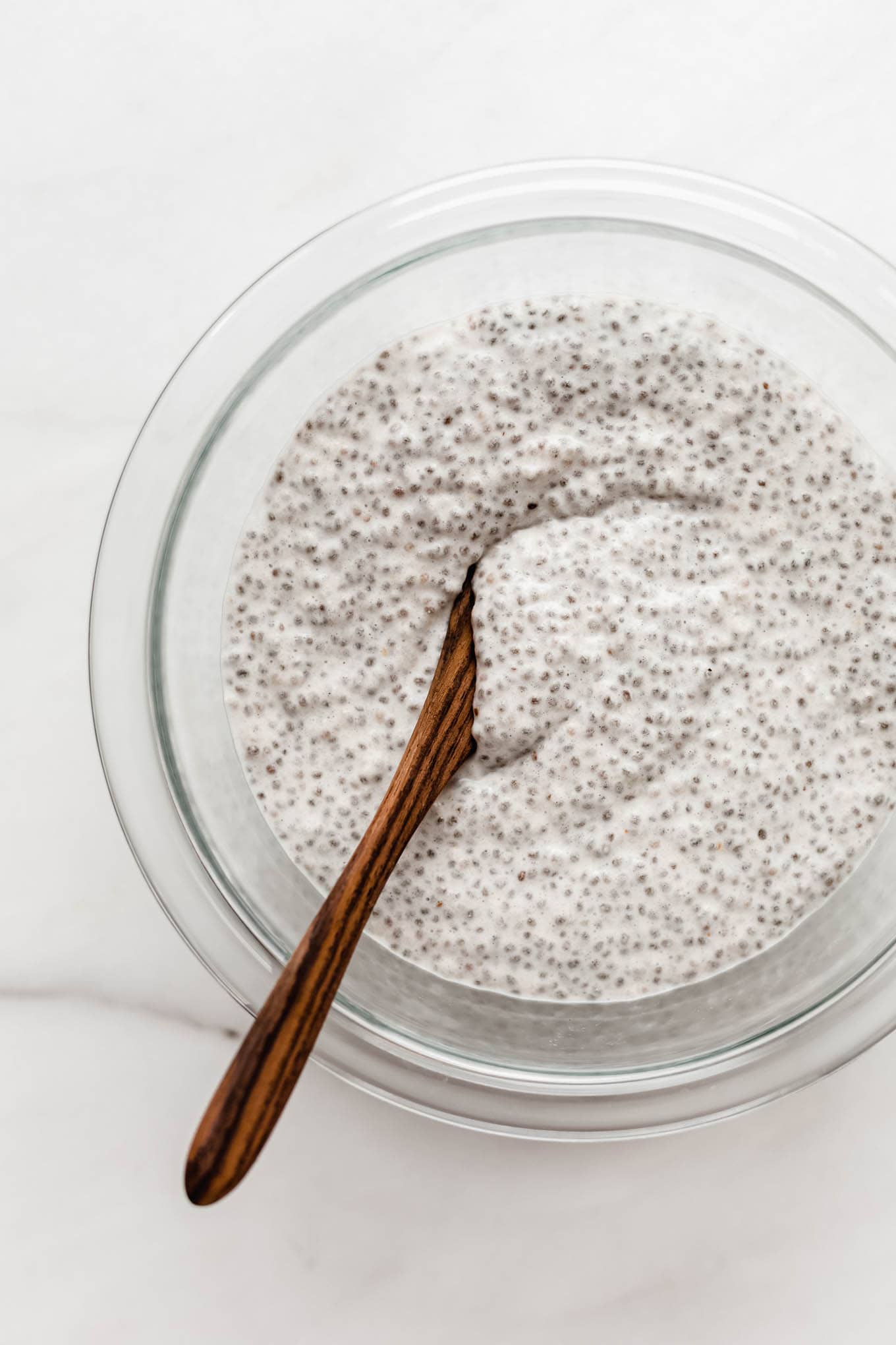 Apple chia pudding in a clear mixing bowl.