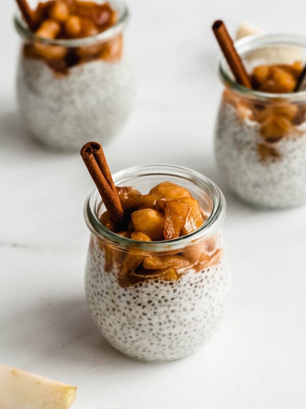three jars of apple chia pudding topped with stewed apples.