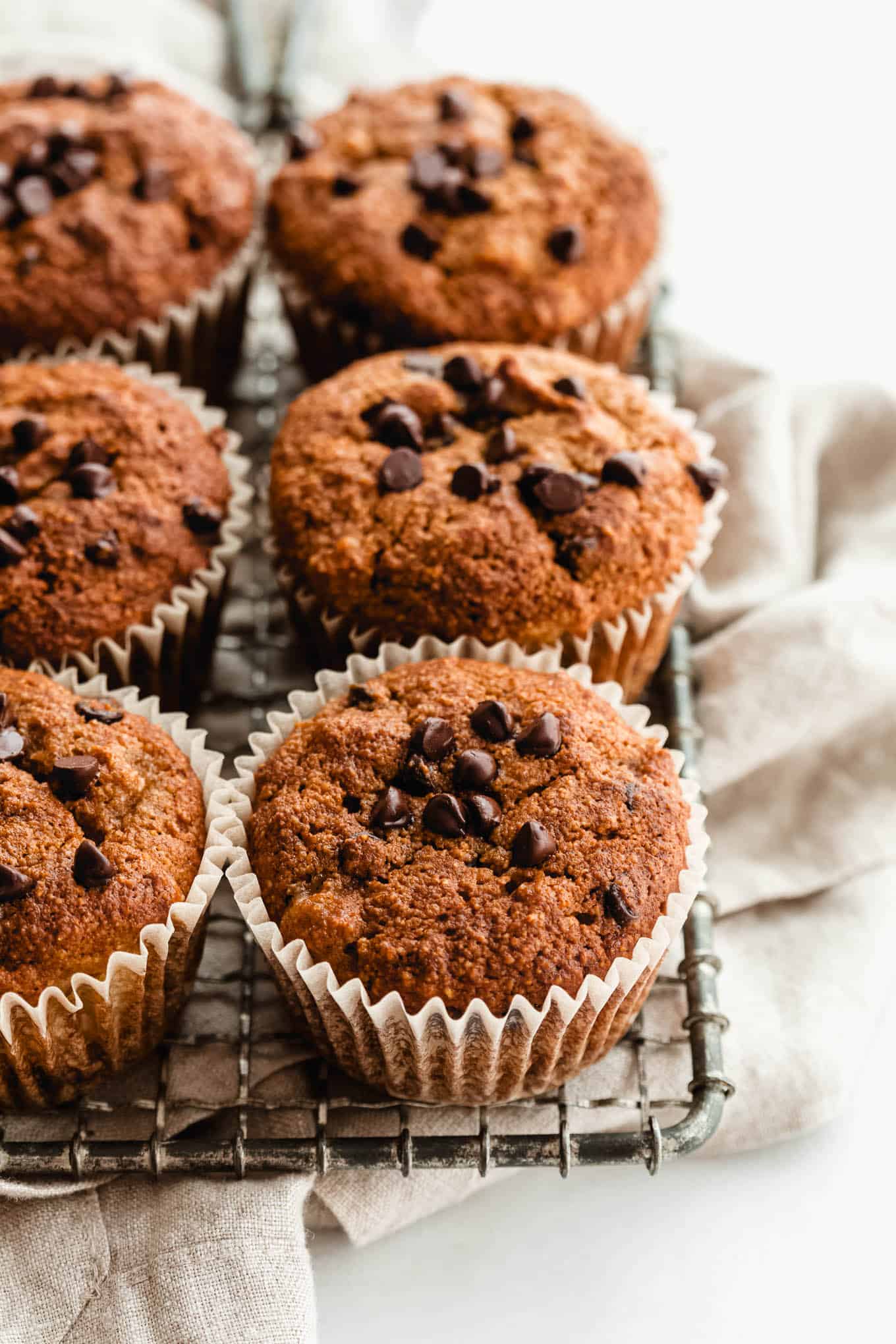 Banana almond flour muffins on a cooling rack and beige napkin.