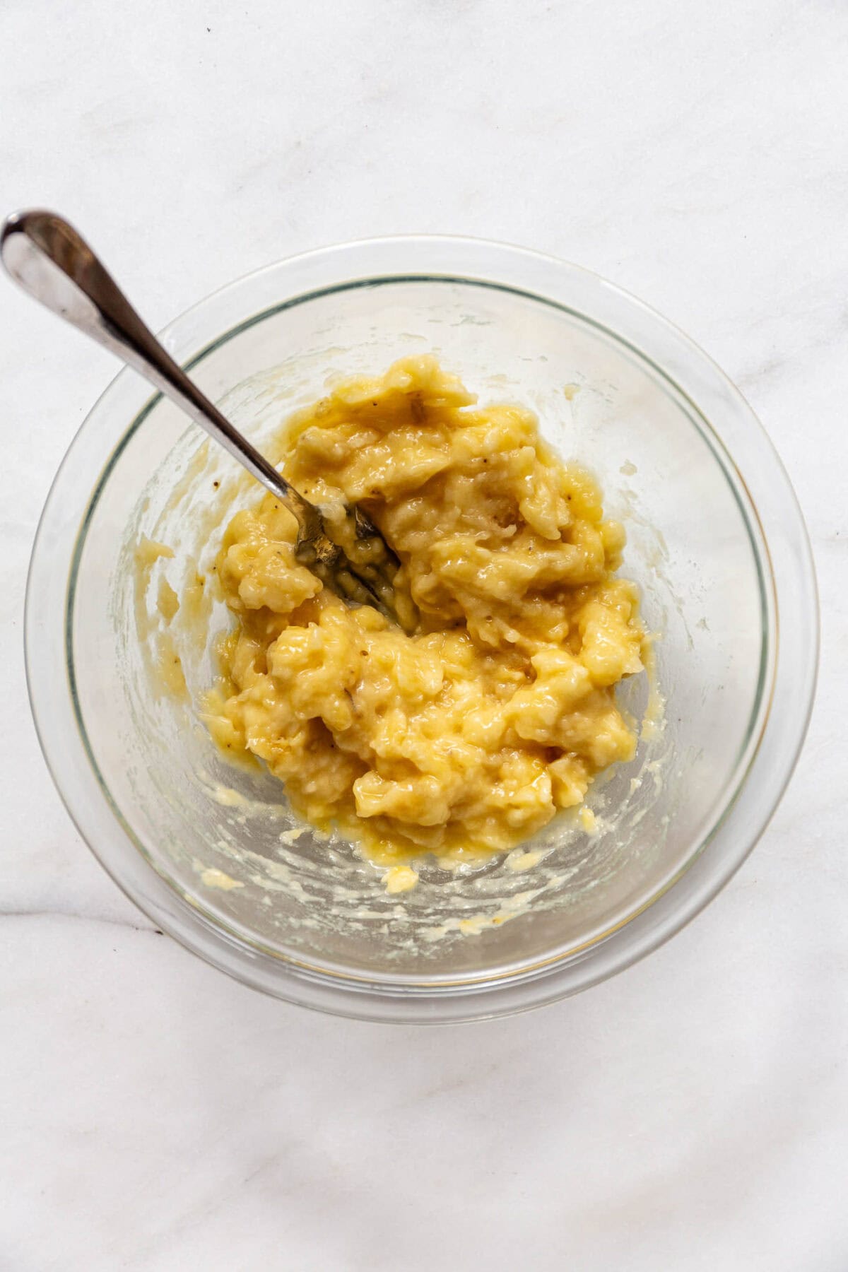 mashed bananas and a fork in a clear bowl.