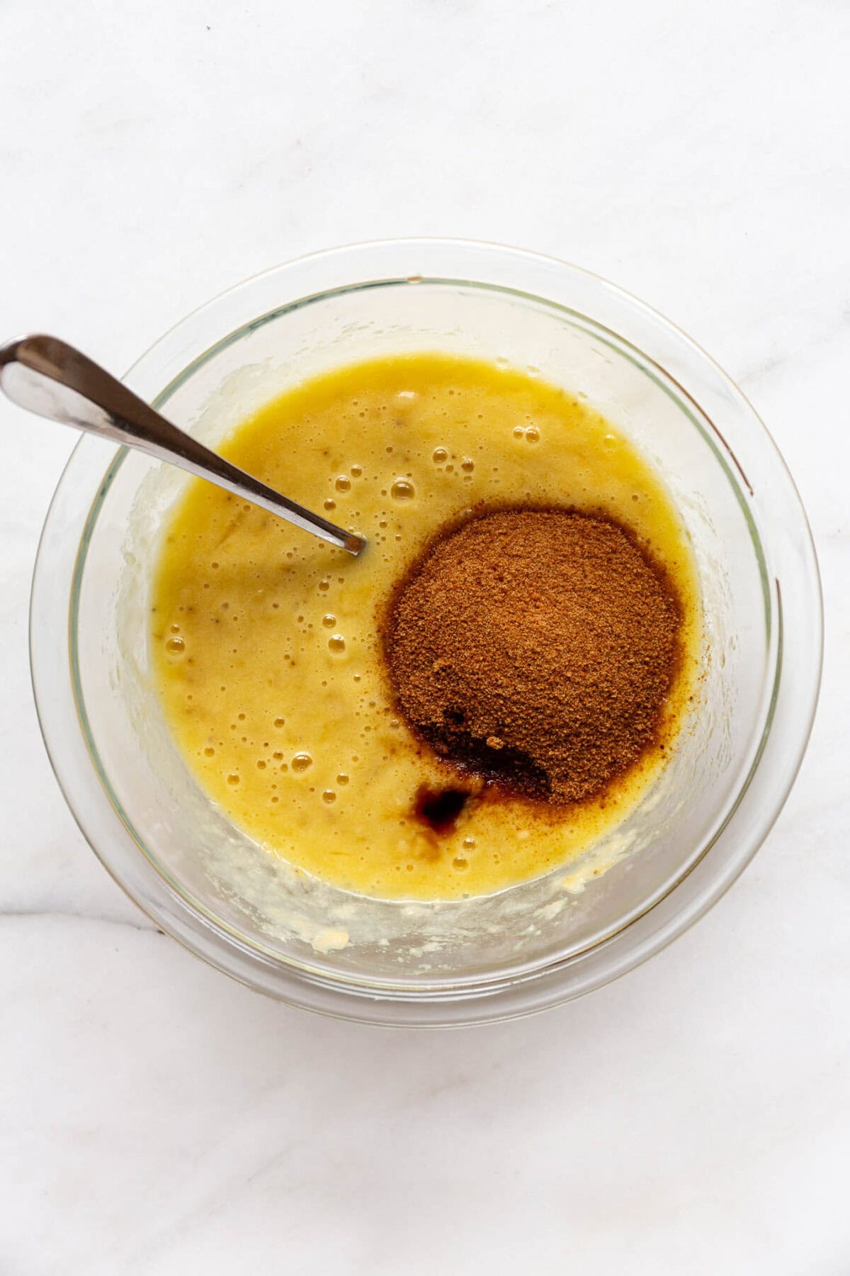 mashed banana mixed with eggs in a bowl with coconut sugar.