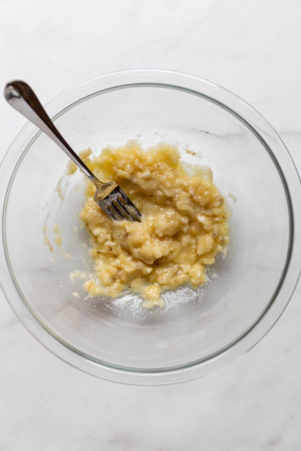 mashed banana in a bowl with a fork.