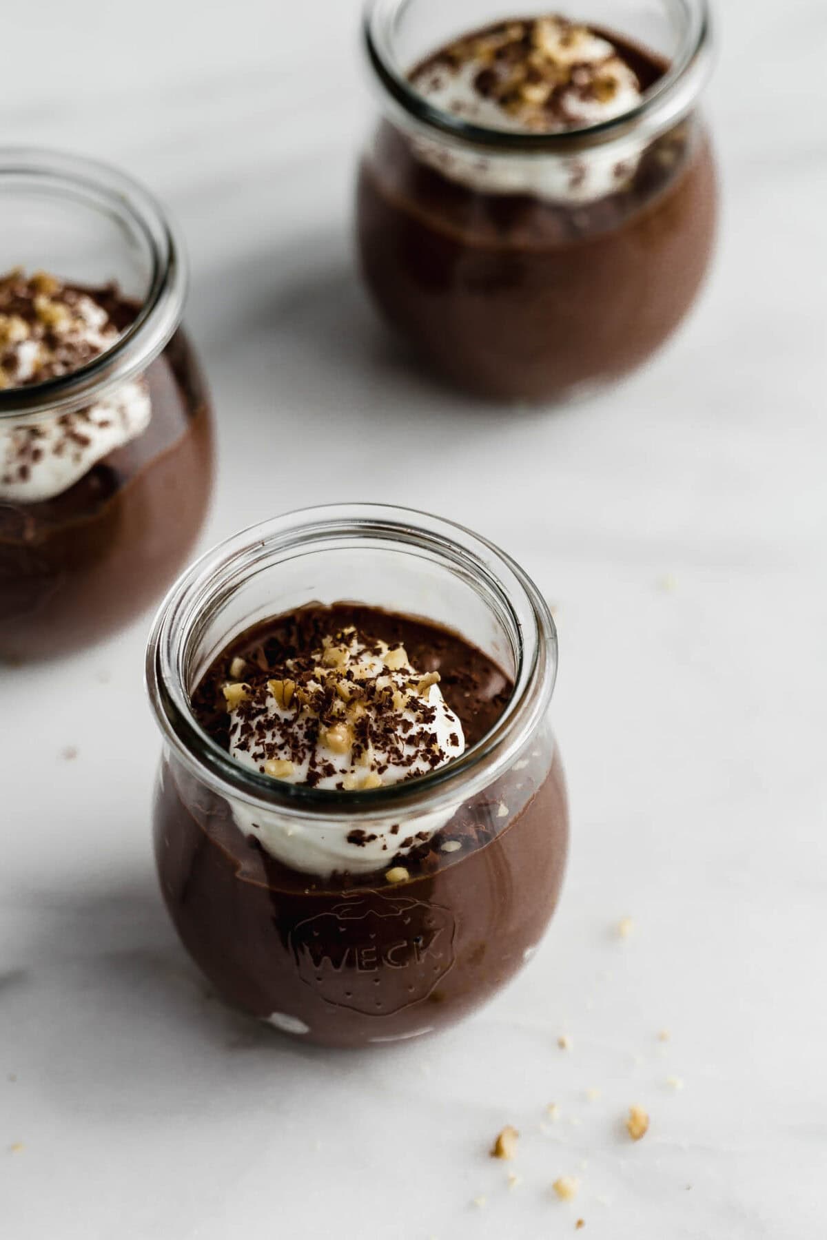 three cups of chocolate chia mousse topped with yogurt.