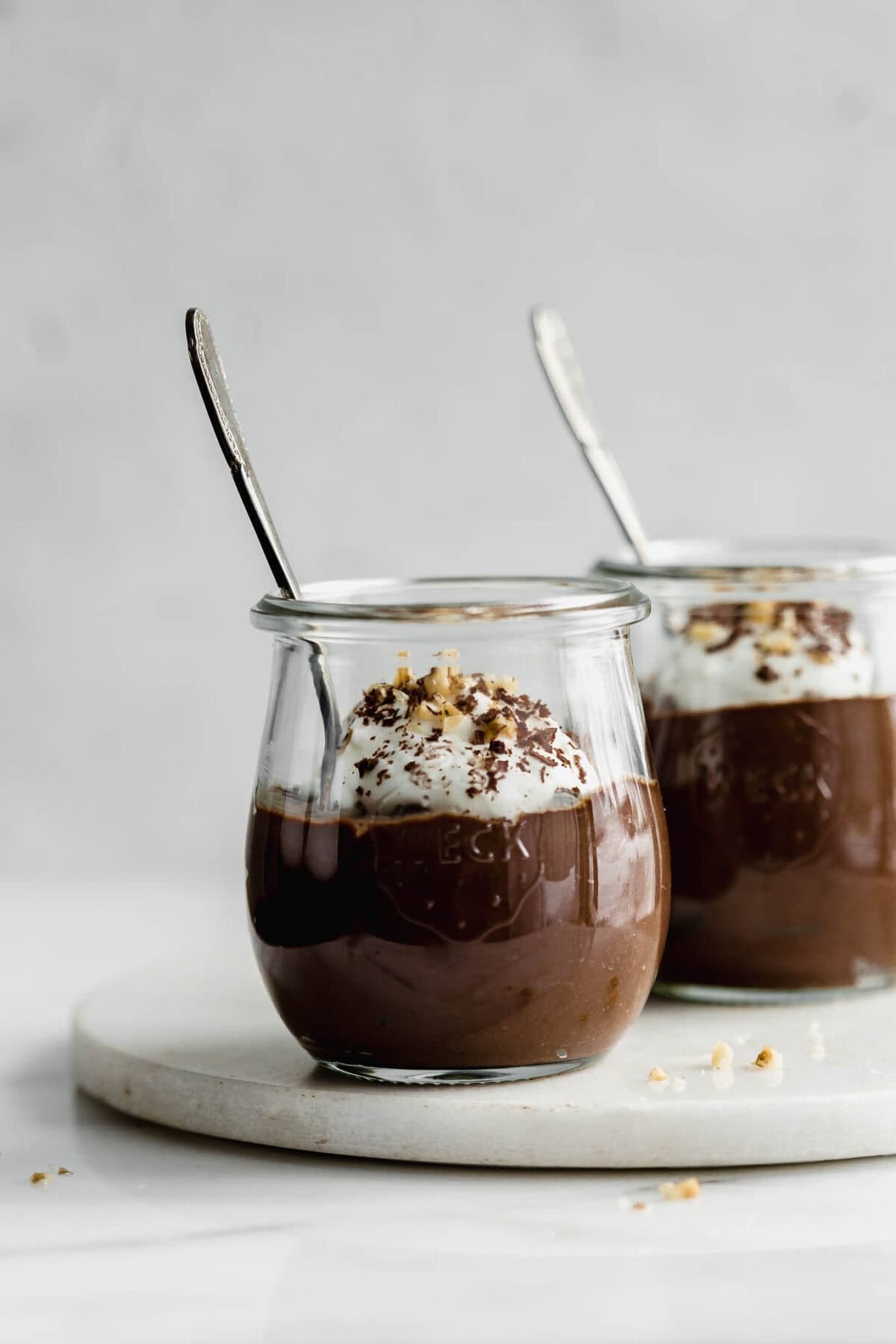two jars of chocolate chia mousse with spoons in them.
