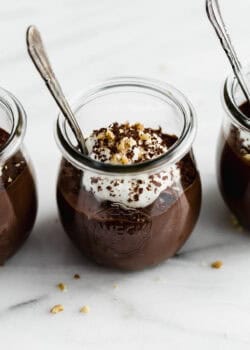 A cup of chocolate chia mousse topped with yogurt, walnuts and chocolate shavings.
