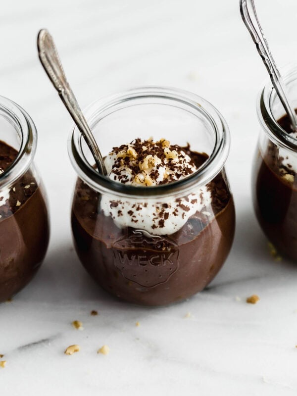 A cup of chocolate chia mousse topped with yogurt, walnuts and chocolate shavings.