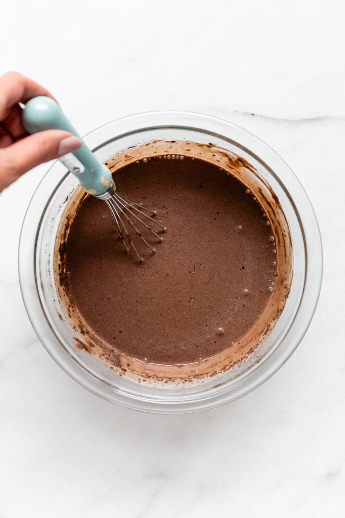 unset chocolate chia mousse in a mixing bowl with a blue whisk.