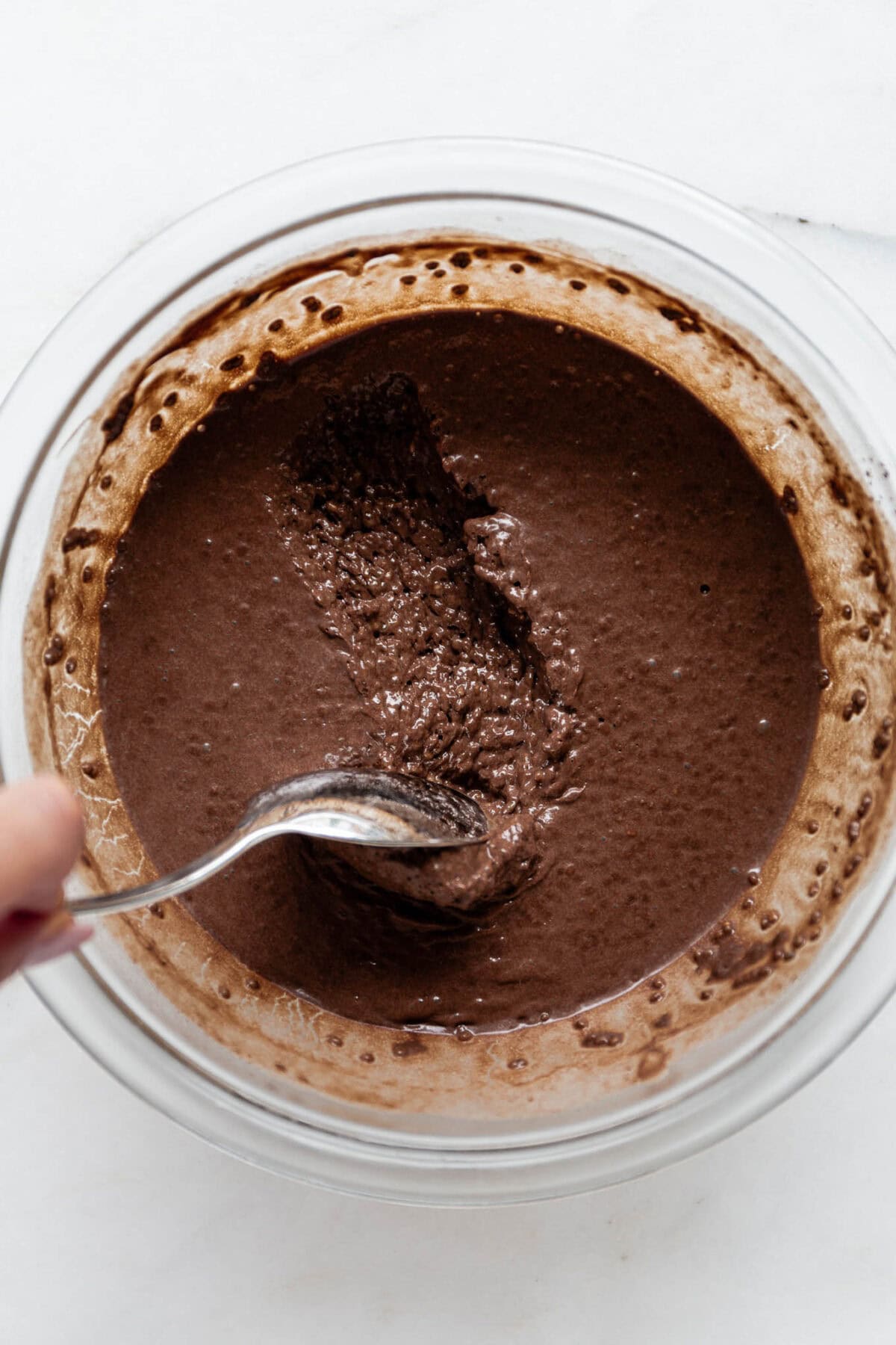 A spoon scooping chocolate chia mousse out of a mixing bowl.