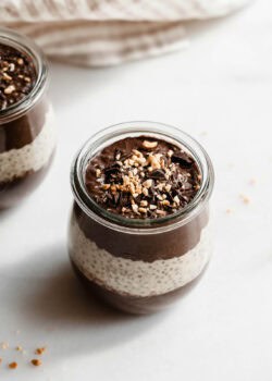 A cup of chocolate peanut butter chia pudding topped with chocolate and peanut butter.