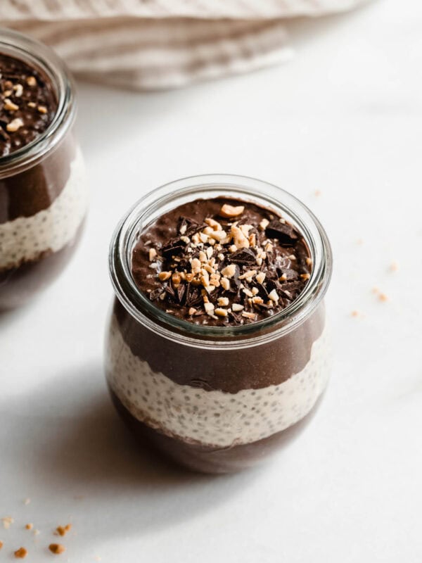 A cup of chocolate peanut butter chia pudding topped with chocolate and peanut butter.