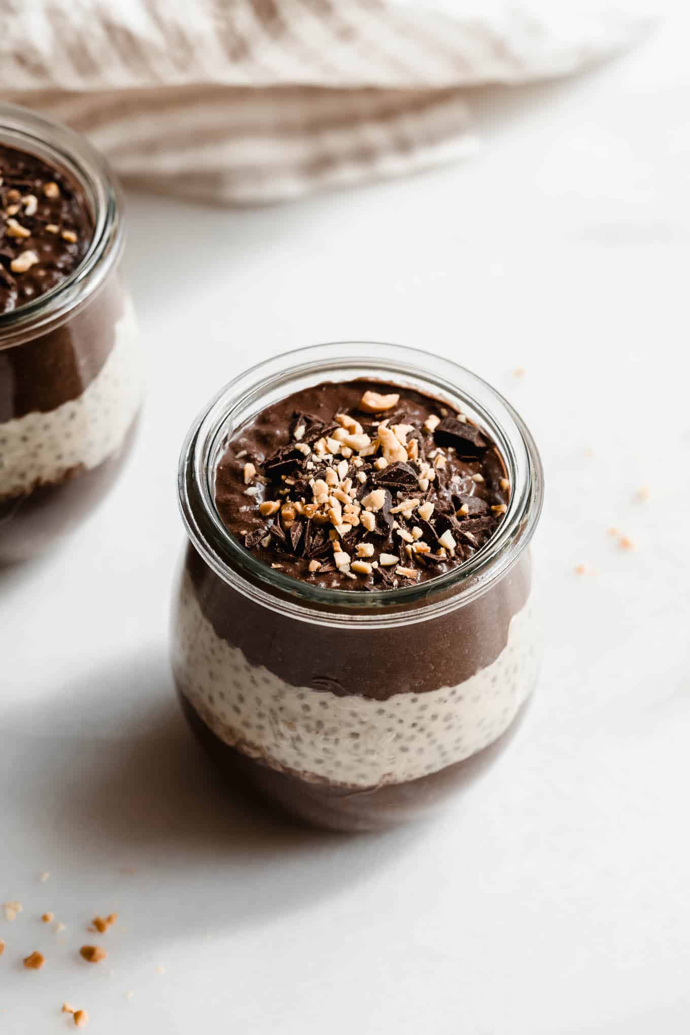 A cup of chocolate peanut butter chia pudding topped with chocolate and peanut butter.
