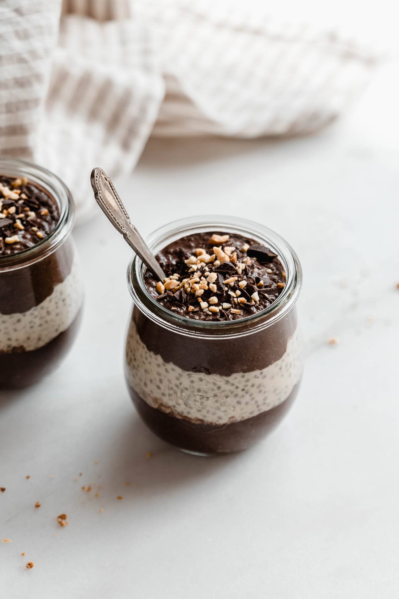 A cup of chocolate peanut butter chia pudding with a spoon in it.
