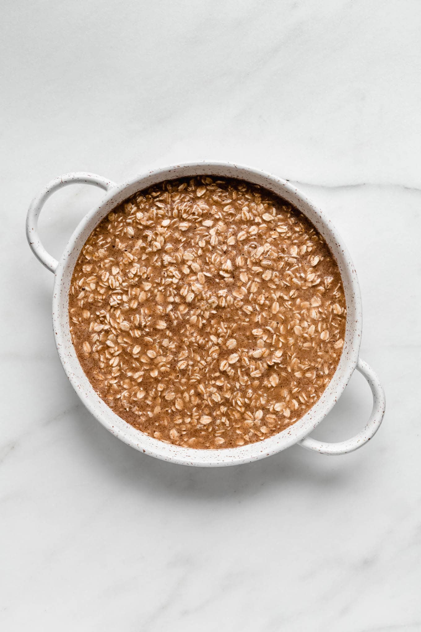 unbaked cinnamon roll baked oats in a round baking dish.