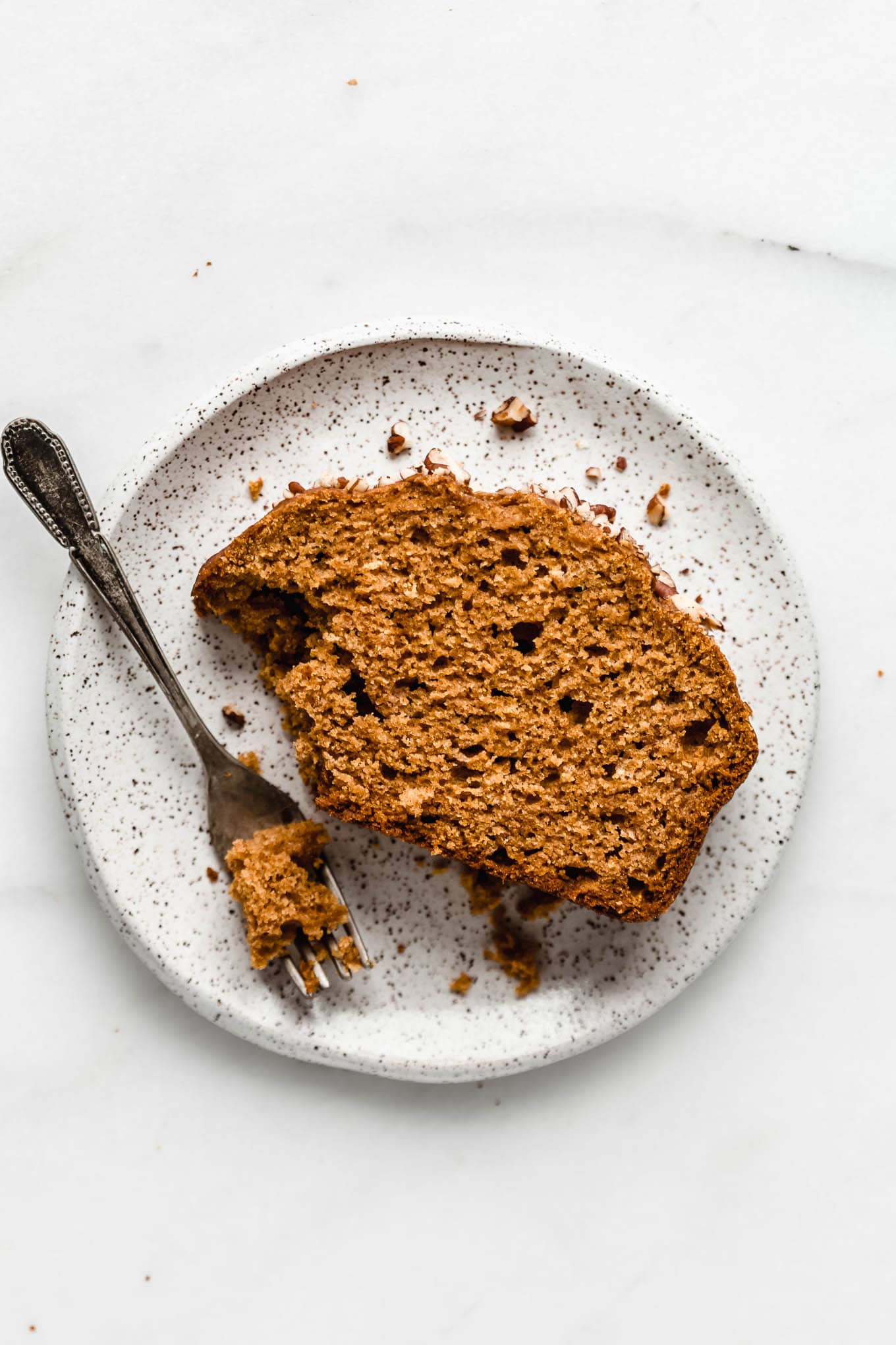 A slice of maple pumpkin bread on a white speckled plate.