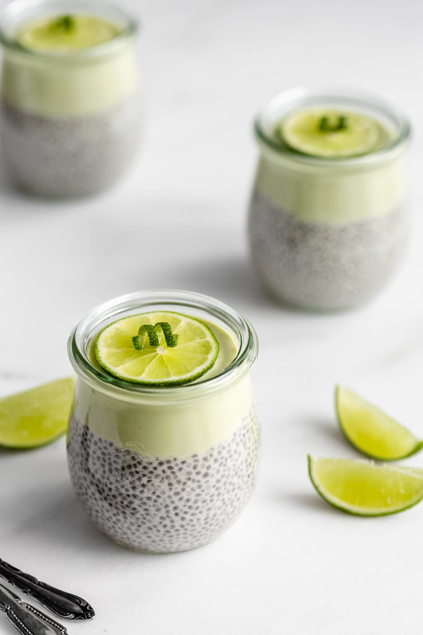 Key lime pie chia pudding cups with lime wedges on the side.