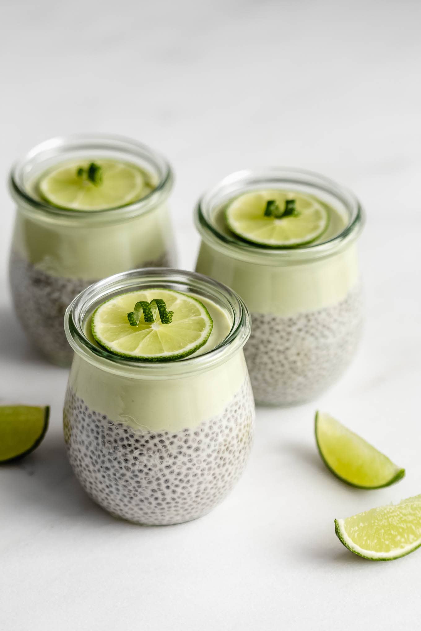 three jars of key lime pie chia pudding topped with a lime wedge.
