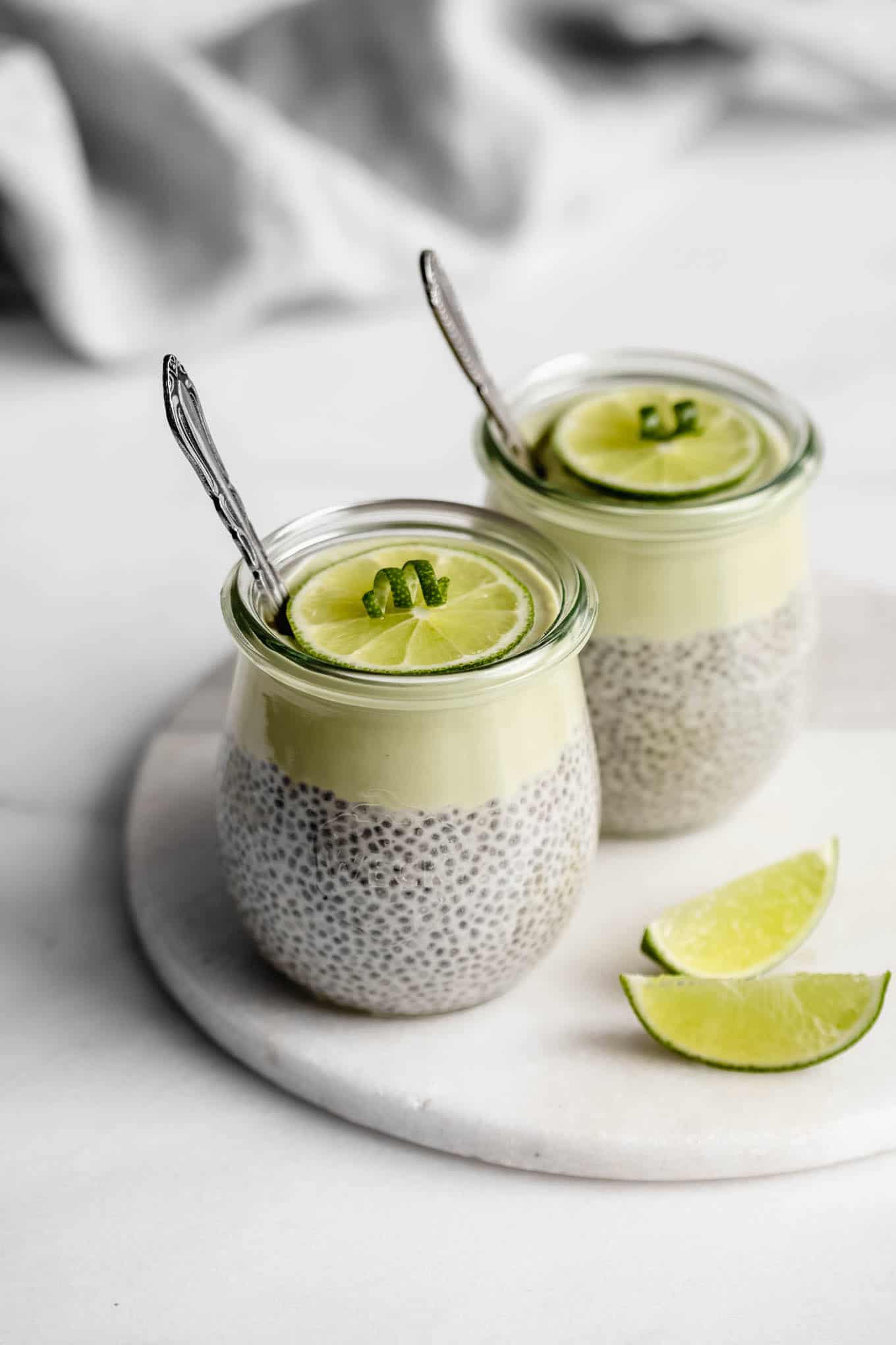 two jars of key lime pie chia pudding on a white marble tray.