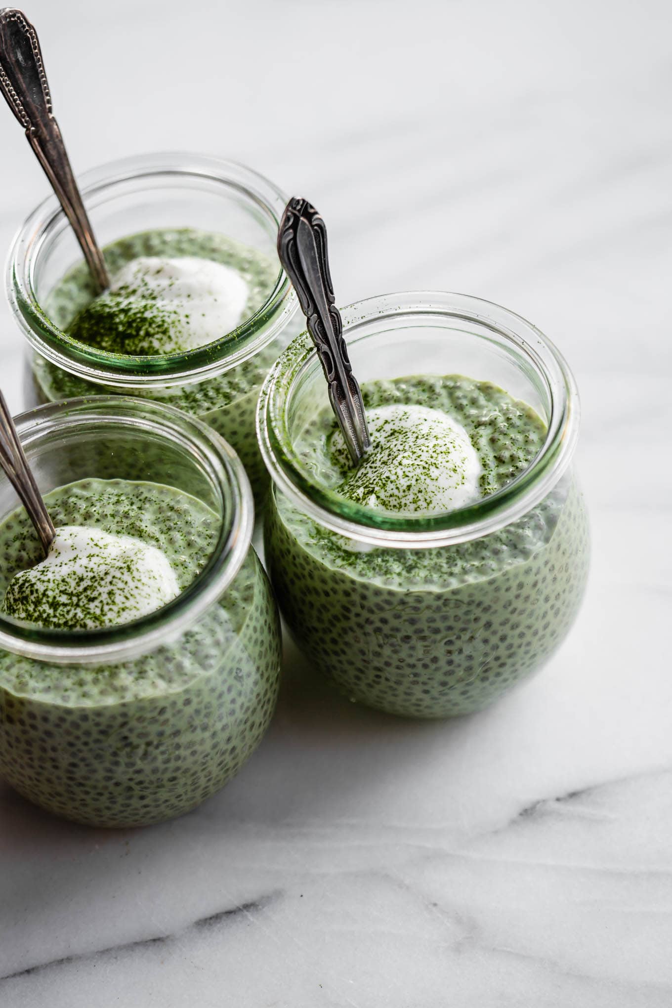thee jars of matcha chia pudding topped with yogurt.