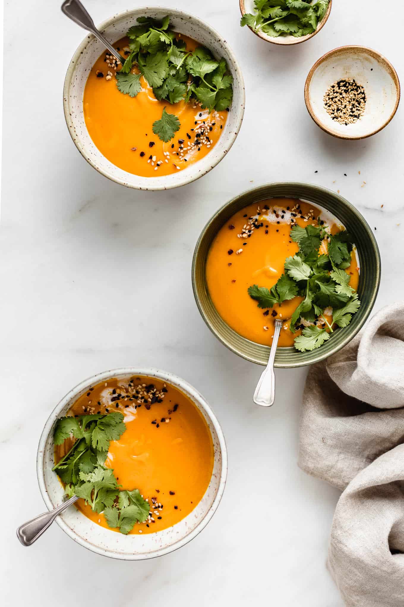 three bowls of Thai butternut squash soup topped with cilantro.