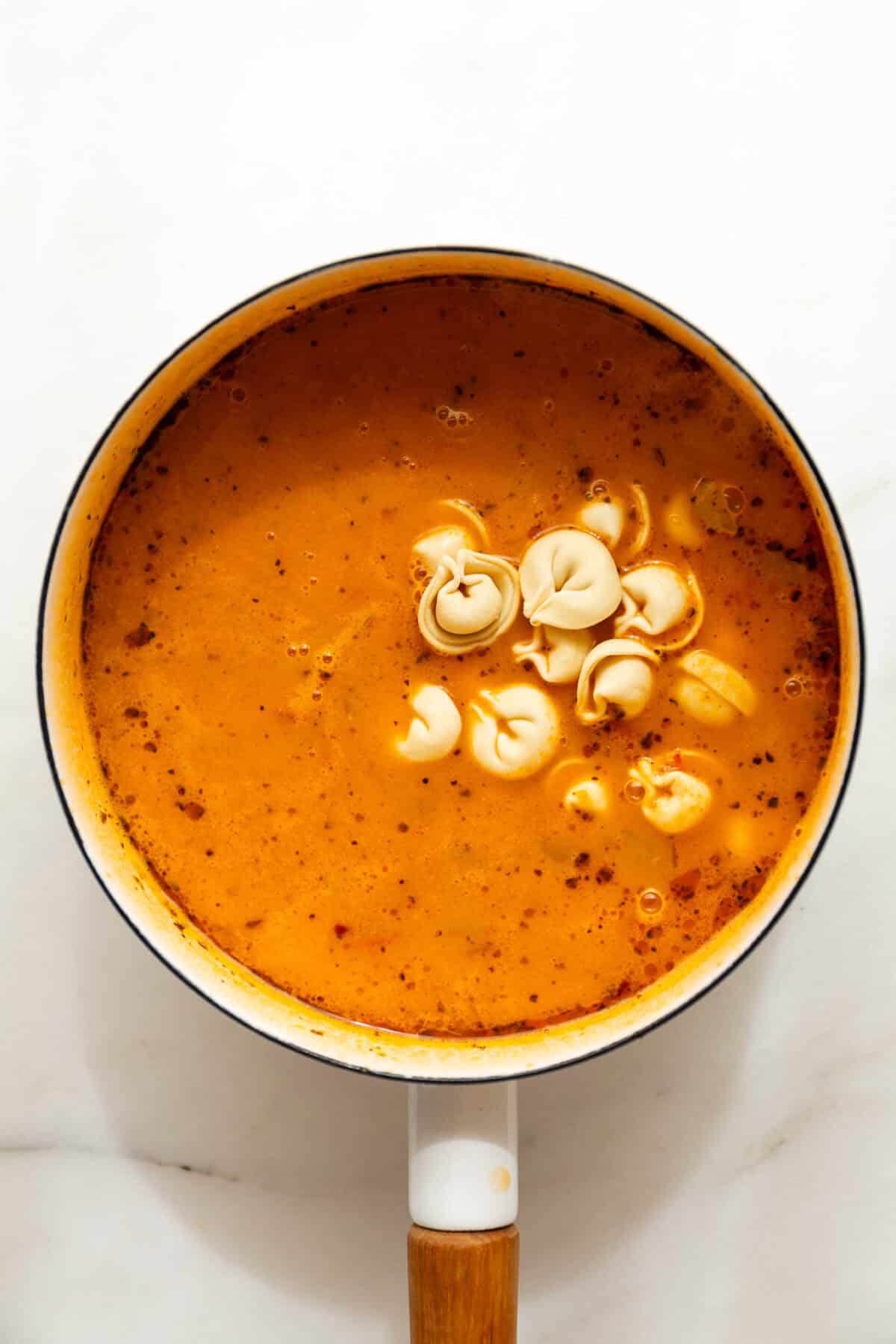 Frozen tortellini in a pot of tuscan soup.