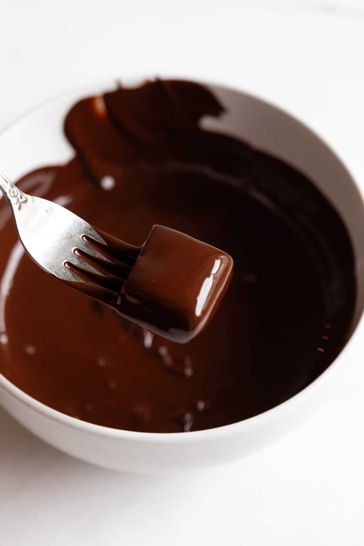 A fork holding a date caramel dipped in chocolate.